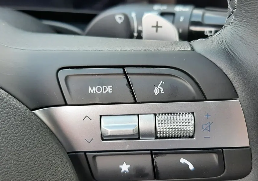 Gros plan sur les commandes du volant cuir noir du Hyundai Tucson 2025, avec molette de volume et bouton mode.