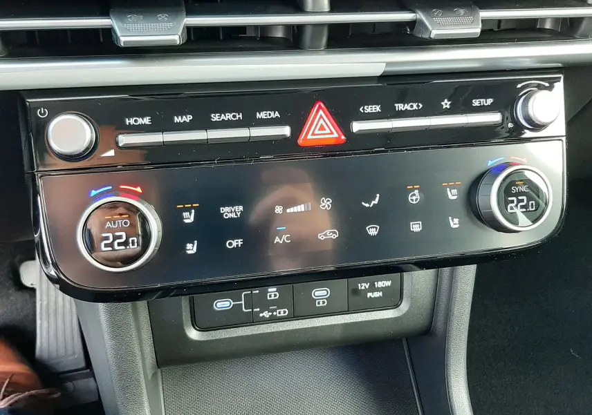 Tableau de bord noir du Hyundai Tucson 2025 avec commandes climatisation digitale et boutons multimédia vus de face.