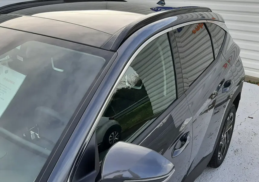 Vue de trois quarts avant droit du Hyundai Tucson gris Ecotronic avec toit panoramique et jantes alliage 19 pouces.