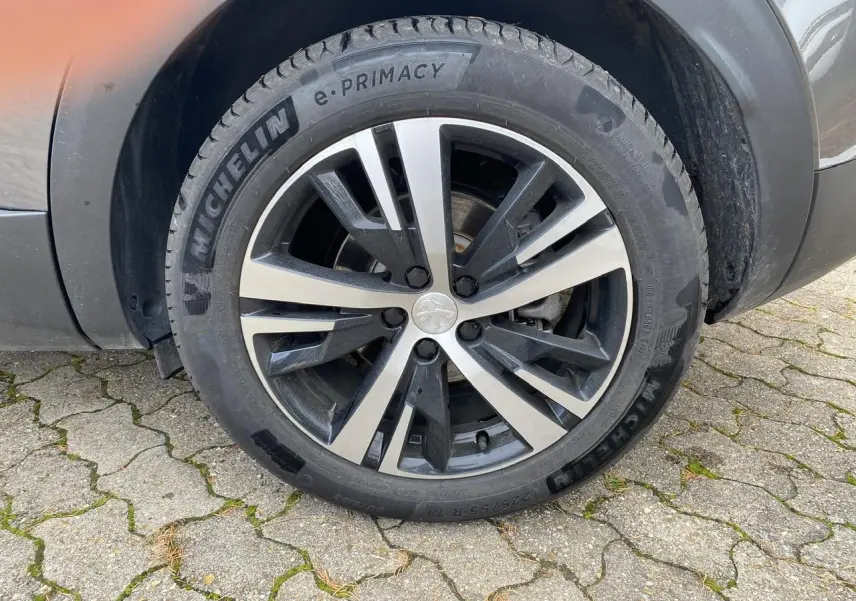 Gros plan sur la roue avant gauche du Peugeot 3008 gris foncé avec jante alliage et pneu Michelin e-Primacy.