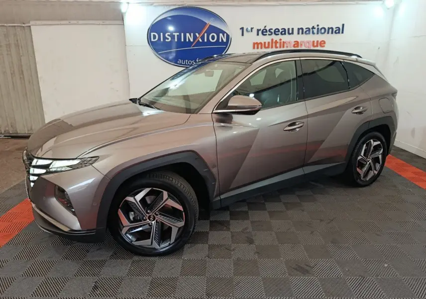 Vue 3/4 avant droite d'un Hyundai Tucson marron 2022 hybride rechargeable dans un showroom intérieur.