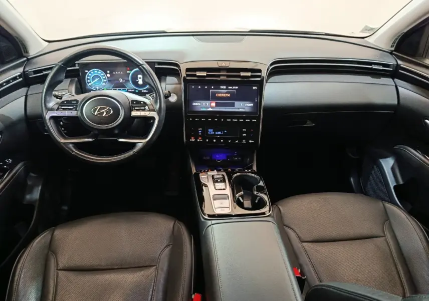 Intérieur noir du Hyundai Tucson 2022, vue frontale sur tableau de bord avec écran tactile et volant multifonctions.