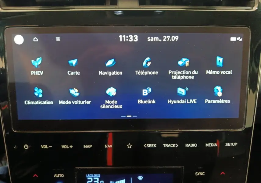 Écran tactile central affichant les options multimédia et navigation du Hyundai Tucson 1.6 PHEV marron, intérieur noir.