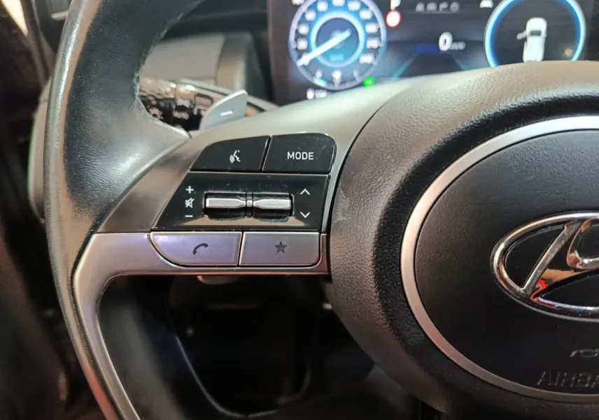 Gros plan sur le côté gauche du volant noir du Hyundai Tucson 2022 avec commandes audio et logo Hyundai visible.