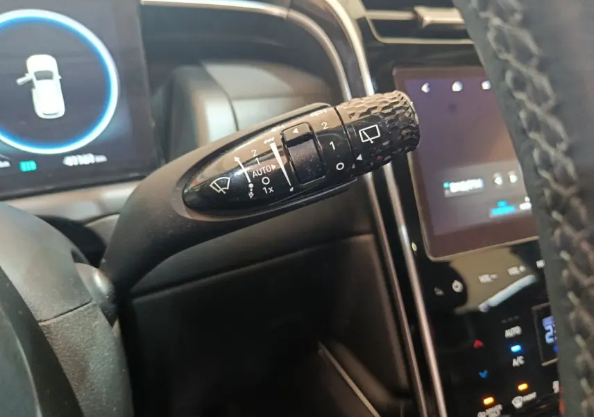 Gros plan sur la commande d'essuie-glace noire à motifs, tableau de bord et écran tactile du Hyundai Tucson marron 2022.