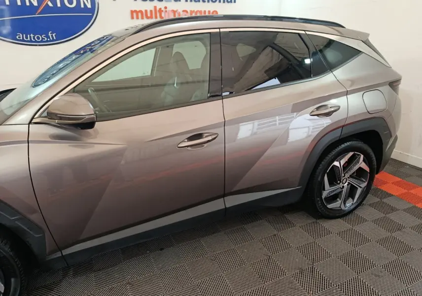 Profil côté gauche d'un Hyundai Tucson marron 2022 avec jantes alliage et lignes anguleuses marquées.