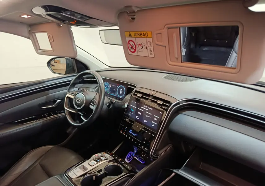 Intérieur du Hyundai Tucson 2022 vu côté conducteur, tableau de bord noir avec écran tactile et volant cuir.