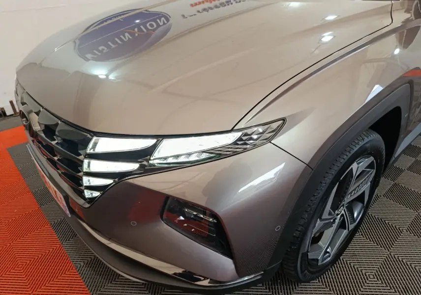 Vue 3/4 avant droit du Hyundai Tucson marron 2022 avec phares LED et jante alliage distinctive.