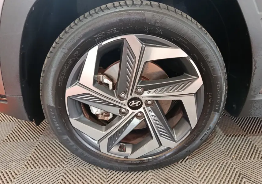 Gros plan sur la roue avant droite du Hyundai Tucson marron 2022 avec jante alliage au design géométrique.