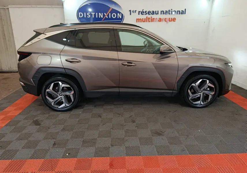Vue de profil côté gauche du Hyundai Tucson marron 2022 hybride rechargeable dans un showroom intérieur.