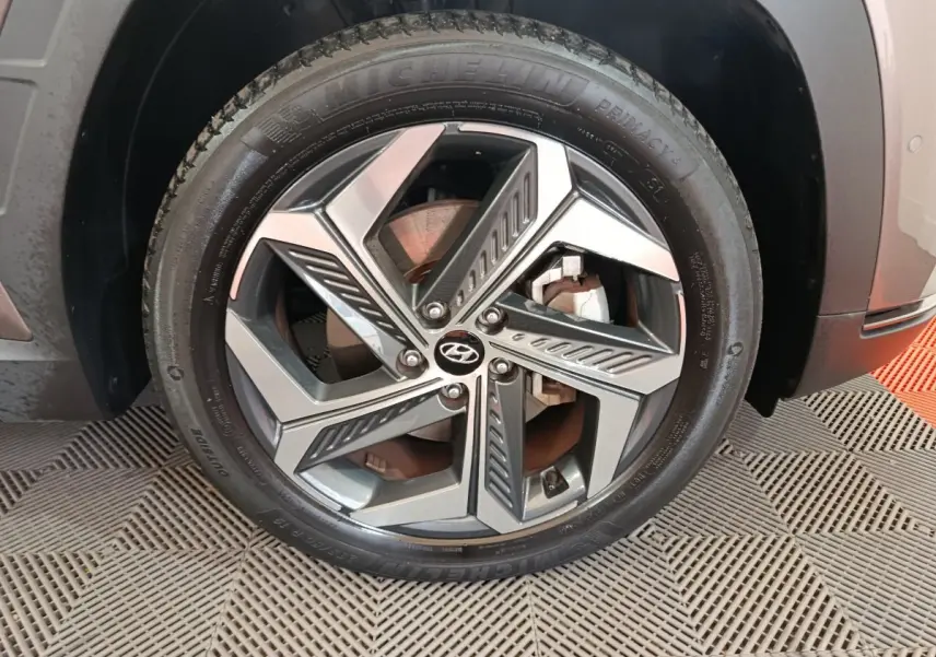 Gros plan sur la roue avant gauche du Hyundai Tucson marron, mettant en valeur la jante alliage au design moderne et le pneu Michelin.