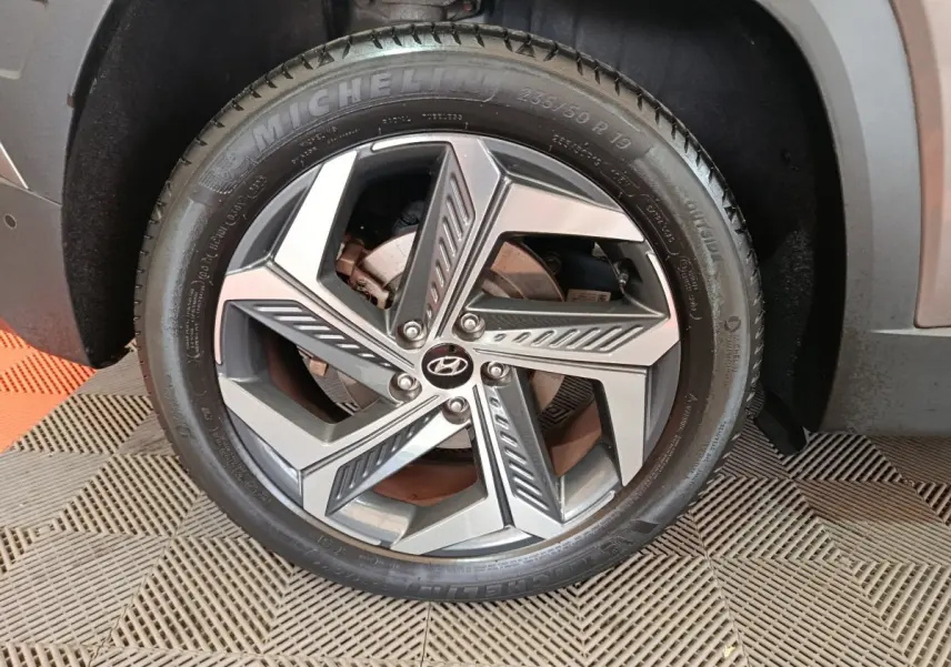 Gros plan sur la roue avant gauche du Hyundai Tucson marron, jante alliage moderne avec logo Hyundai central.