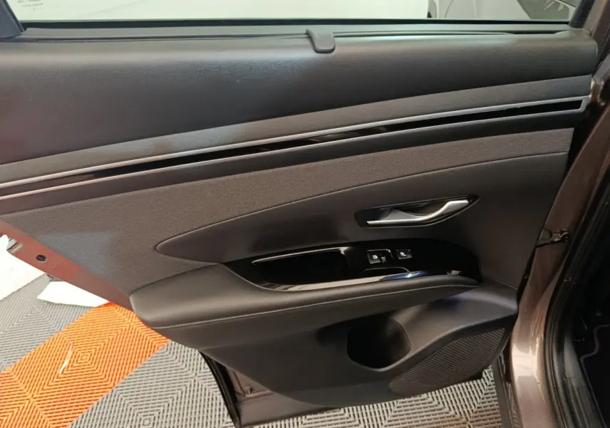 Gros plan sur la porte arrière gauche marron du Hyundai Tucson 2022 avec commandes de vitres et poignée argentée.