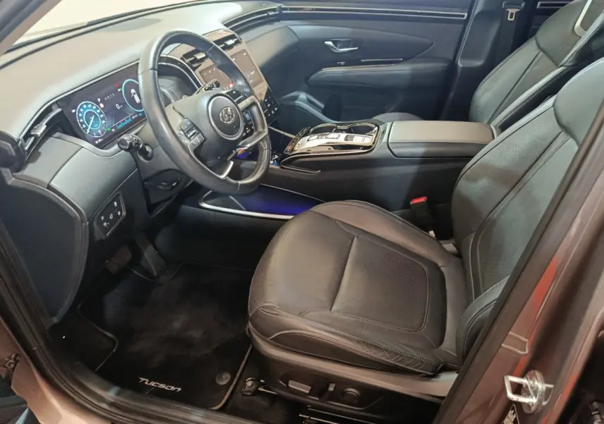 Intérieur avant droit du Hyundai Tucson marron 2022, avec tableau de bord digital et sièges cuir noirs.