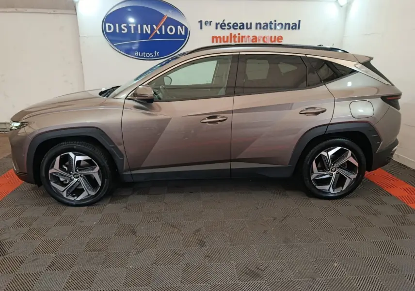 Profil droit d'un Hyundai Tucson marron 2022 hybride rechargeable avec jantes alliage et lignes anguleuses marquées.