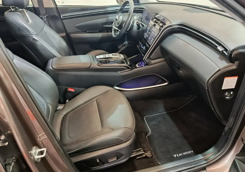 Intérieur avant droit du Hyundai Tucson marron 2022 avec sièges cuir noirs et grand écran tactile central.