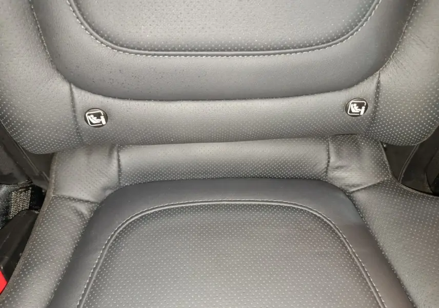 Gros plan sur la partie inférieure d'un siège arrière en cuir noir avec indicateurs Isofix visibles.