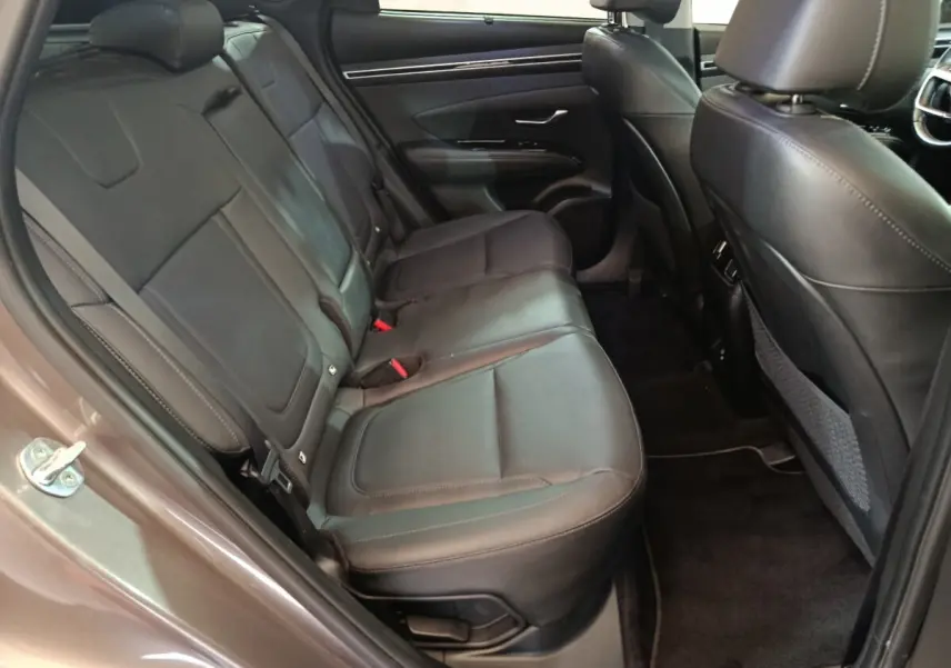 Vue côté gauche des sièges arrière en cuir noir du Hyundai Tucson 2022 marron, avec porte ouverte et intérieur spacieux.