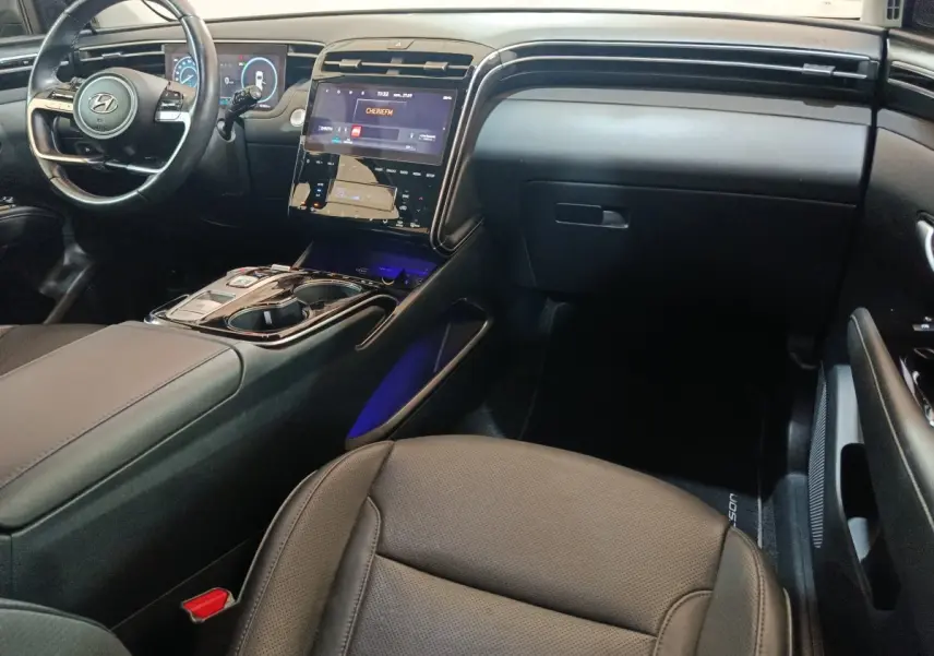 Vue intérieure côté passager du tableau de bord et console centrale noire du Hyundai Tucson 2022 hybride rechargeable.