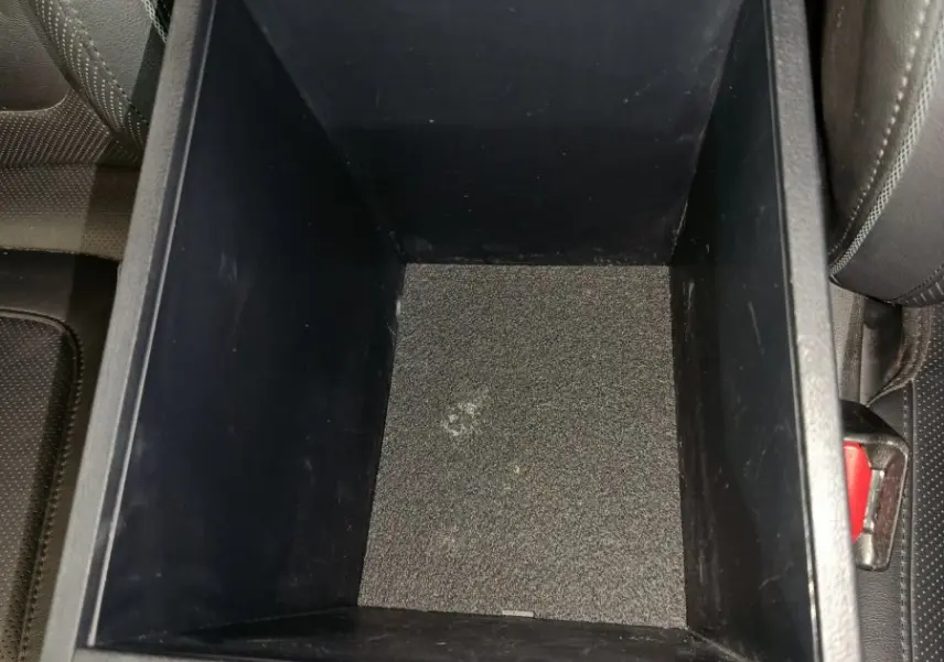 Vue plongeante sur le rangement central noir entre les sièges avant du Hyundai Tucson 2022 marron.