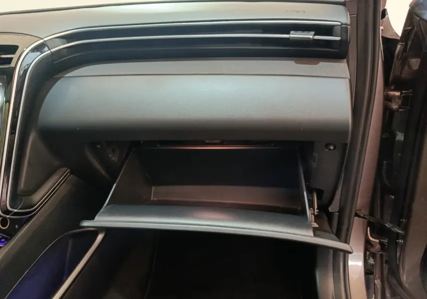 Intérieur du Hyundai Tucson 2022 marron, vue sur la boîte à gants ouverte côté passager avec tableau de bord noir.