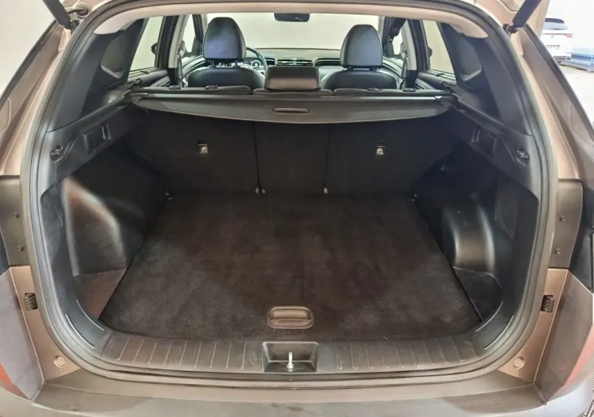 Coffre ouvert vu de l'arrière d'un Hyundai Tucson marron 2022, montrant l'espace de chargement et la tablette arrière.