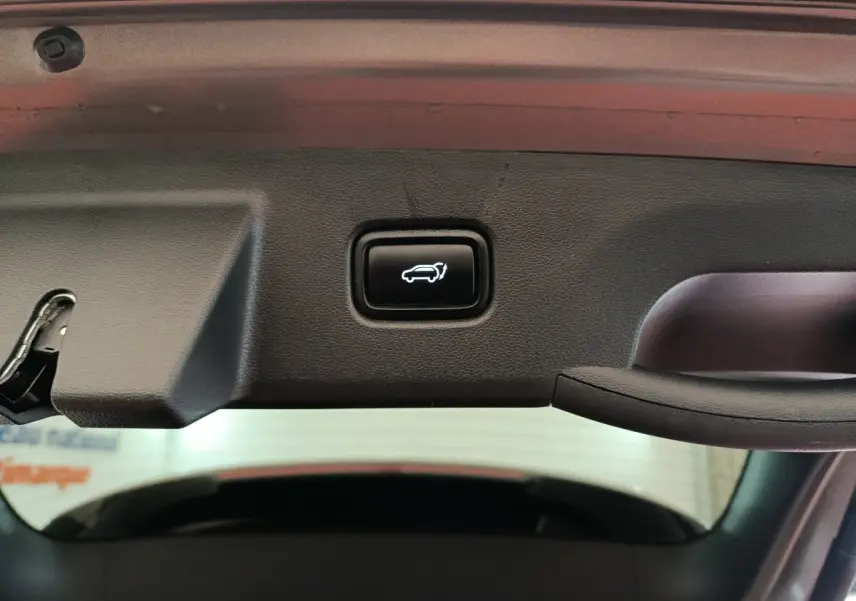 Bouton d'ouverture électrique du coffre sur la partie intérieure du hayon d'un Hyundai Tucson marron 2022.