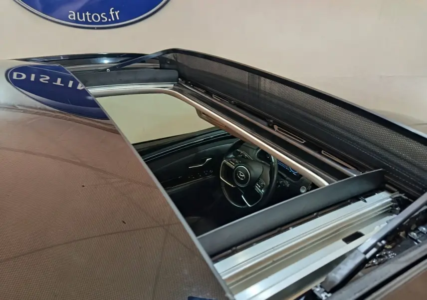Vue rapprochée du toit ouvrant panoramique ouvert du Hyundai Tucson marron, montrant l'intérieur côté conducteur.