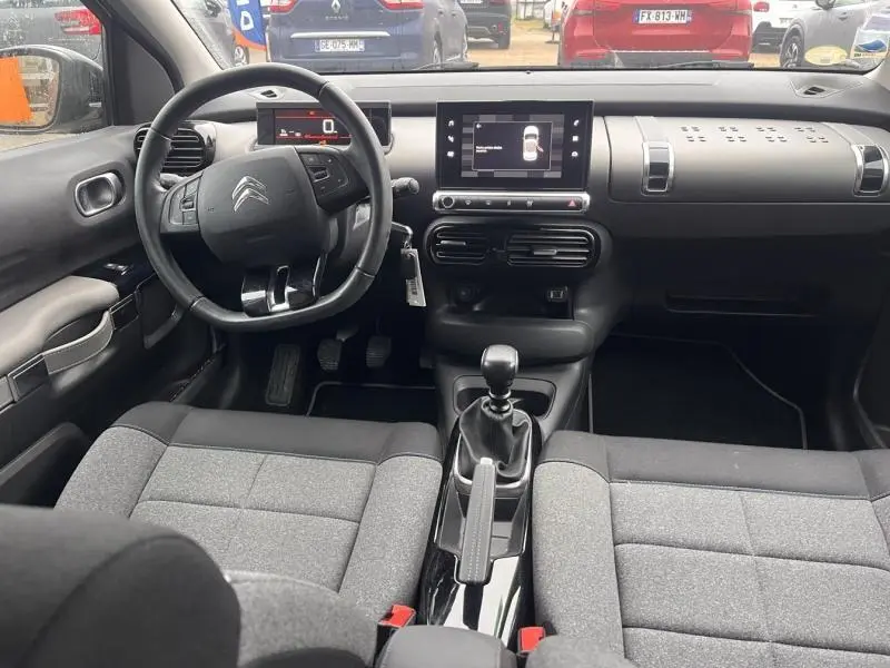Vue intérieure avant du Citroën C4 Cactus 2020 avec tableau de bord noir, volant cuir, écran tactile et sièges gris Mica.