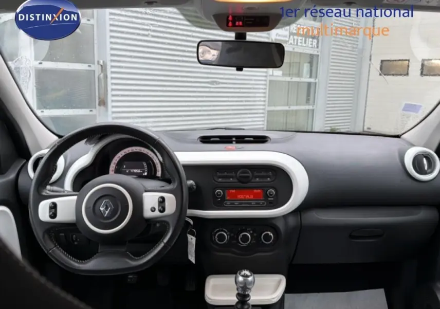 Vue intérieure avant de la Renault Twingo III gris foncé, volant cuir, tableau de bord avec commandes et boîte manuelle.