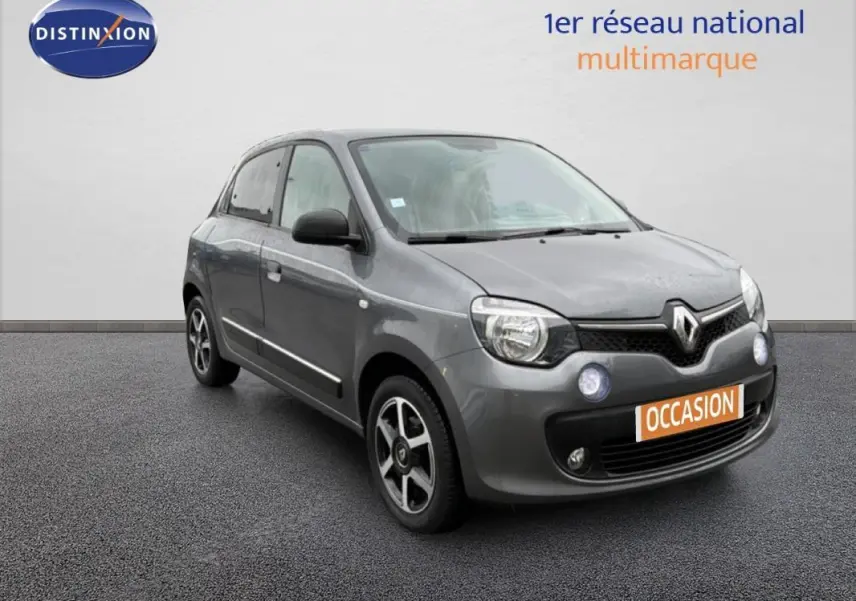 Renault Twingo III gris foncé vue 3/4 avant droit, avec jantes alliage et phares antibrouillard allumés.