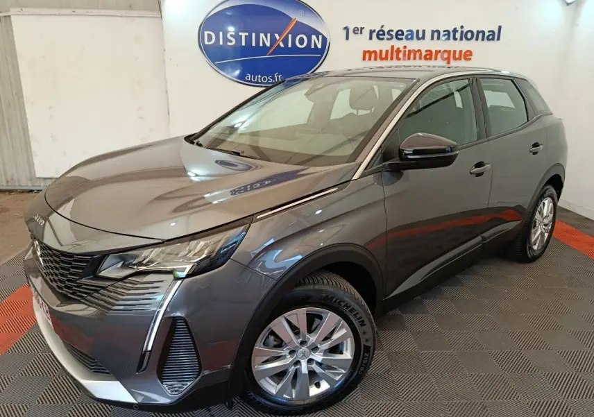 Peugeot 3008 gris foncé vue 3/4 avant droit, avec feux LED et calandre noire distinctive en showroom.