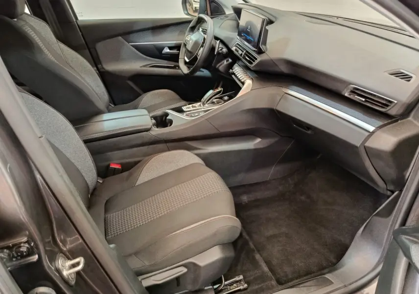 Vue intérieure côté passager avant du Peugeot 3008 gris foncé, avec tableau de bord digital et console centrale moderne.