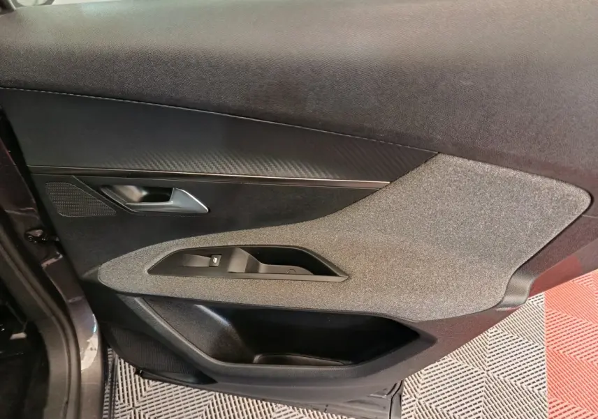Vue côté gauche de la porte intérieure gris foncé du Peugeot 3008 avec insert tissu et commande de vitre.