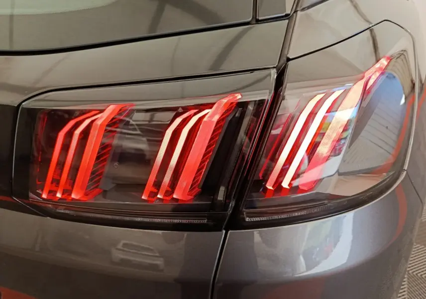 Gros plan sur les feux arrière droits rouges d’un Peugeot 3008 gris foncé, soulignant le design moderne du véhicule.