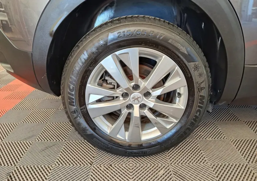 Gros plan sur la roue avant droite grise d’un Peugeot 3008 2022 avec jante alliage et pneu Michelin hiver.