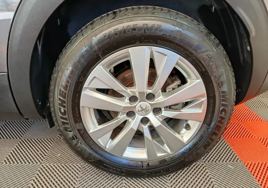 Gros plan sur la roue avant droite d’un Peugeot 3008 gris foncé, avec jante alliage et pneu Michelin visible.