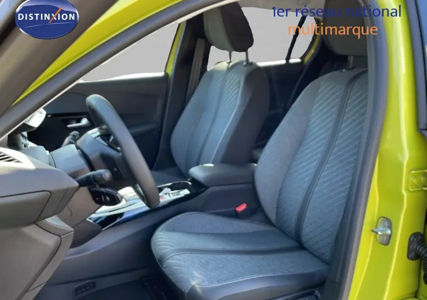 Vue intérieure côté conducteur de la Peugeot 208 Hybrid jaune Agueda, sièges tissu gris avec motifs diagonaux.