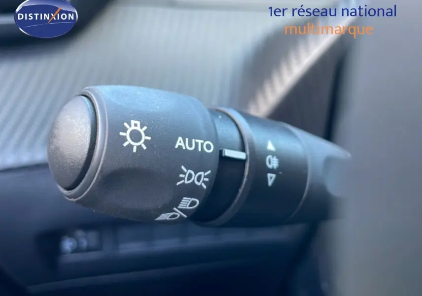 Gros plan sur la commande des feux automatique dans l’habitacle d’une Peugeot 208 Hybrid jaune Agueda Metal.