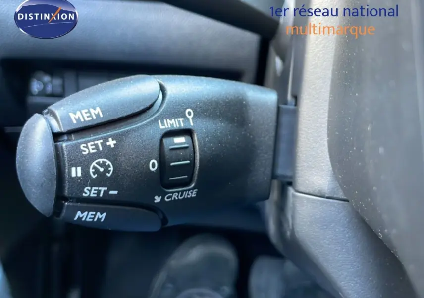 Gros plan sur la commande de régulateur de vitesse dans l'habitacle noir d'une Peugeot 208 jaune Agueda Metal.