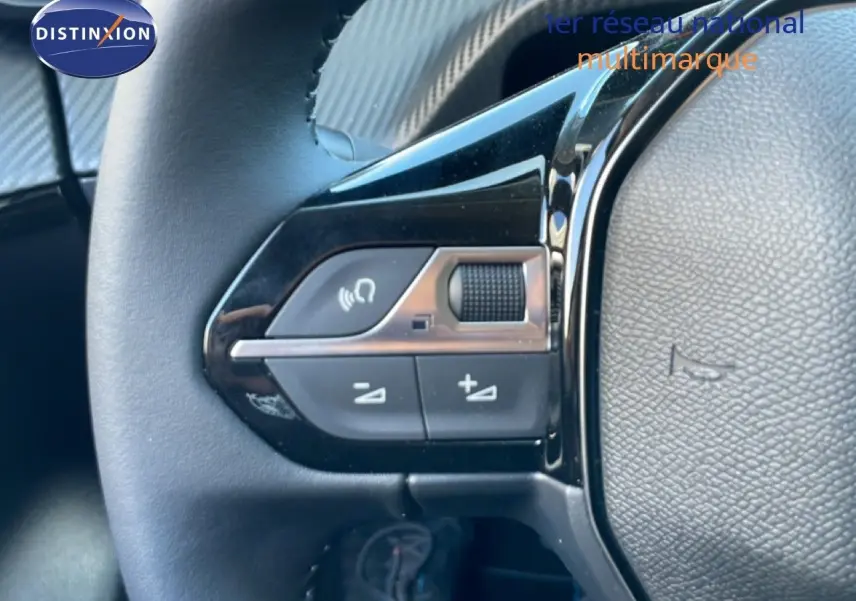 Gros plan sur les commandes de volume au volant d'une Peugeot 208 Hybrid jaune Agueda Metal, intérieur noir.