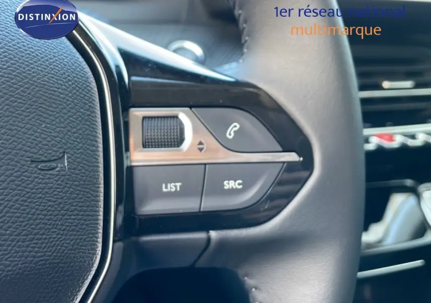 Gros plan sur les commandes gauche du volant en cuir noir d'une Peugeot 208 jaune Agueda Metal, version hybride 2026.