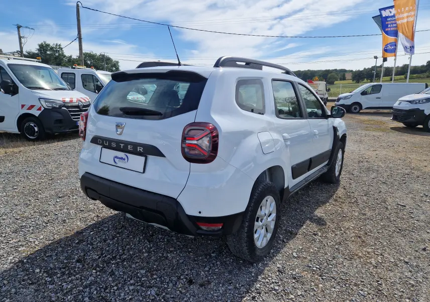 Vue 3/4 arrière droite d'un Dacia Duster blanc 4x4 2023 avec protections noires et jantes alliage 16 pouces.