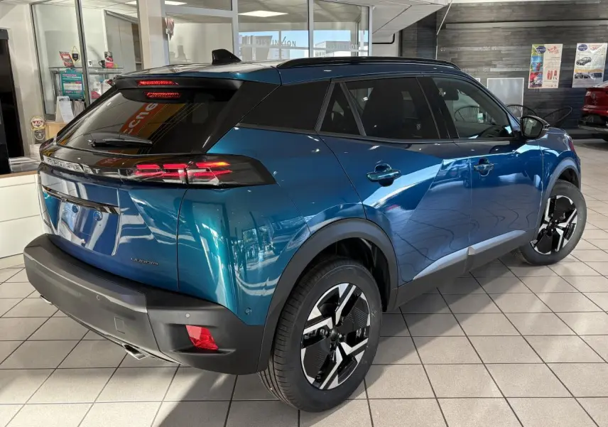 Peugeot 2008 bleu en 3/4 arrière droit, avec toit noir, feux LED à 3 griffes et jantes alliage bi-ton 17 pouces.