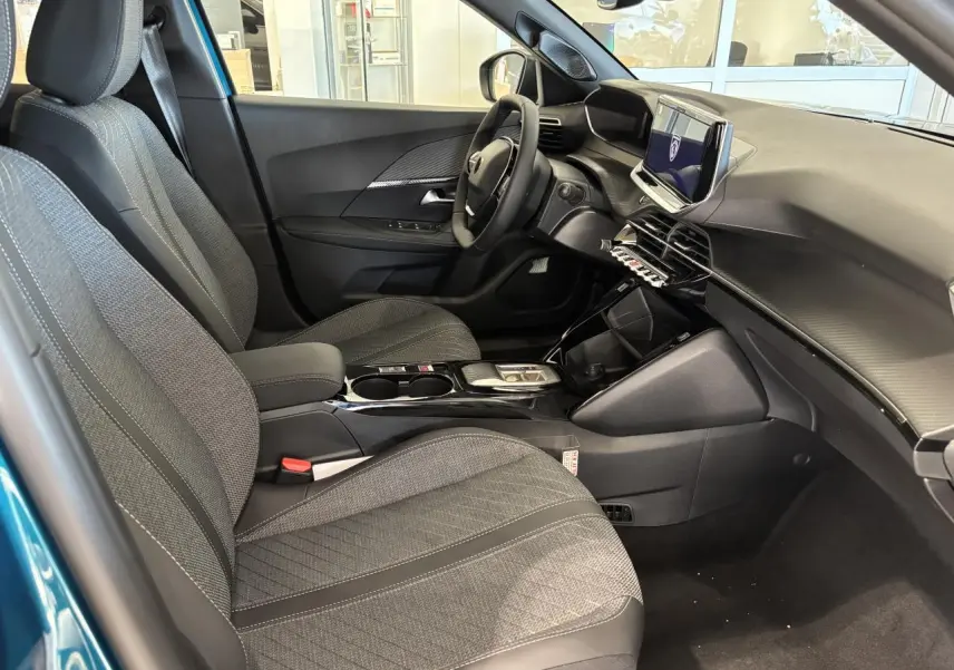 Vue intérieure côté conducteur du Peugeot 2008 bleu, avec sellerie tissu gris et tableau de bord moderne noir.