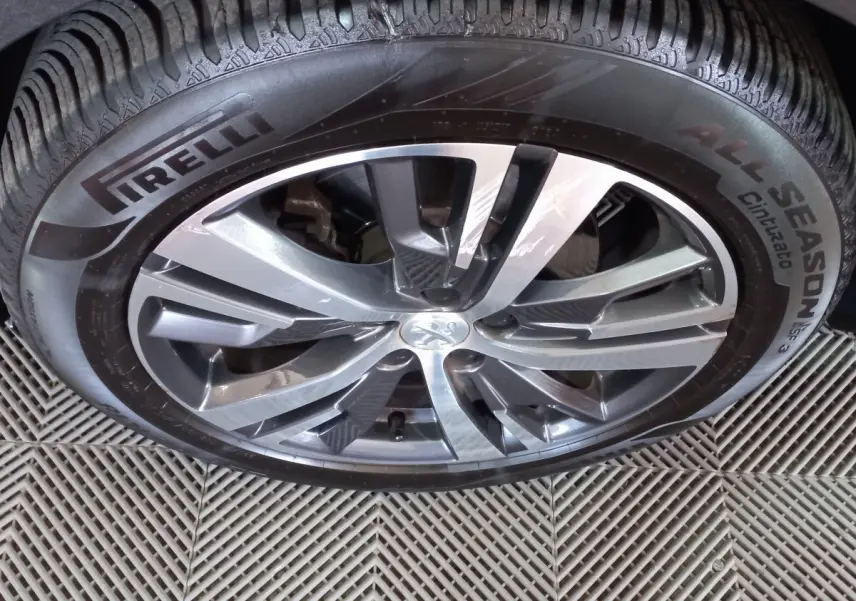 Gros plan sur la jante alliage gris foncé avec logo Peugeot et pneu Pirelli All Season sur Peugeot 5008 2021