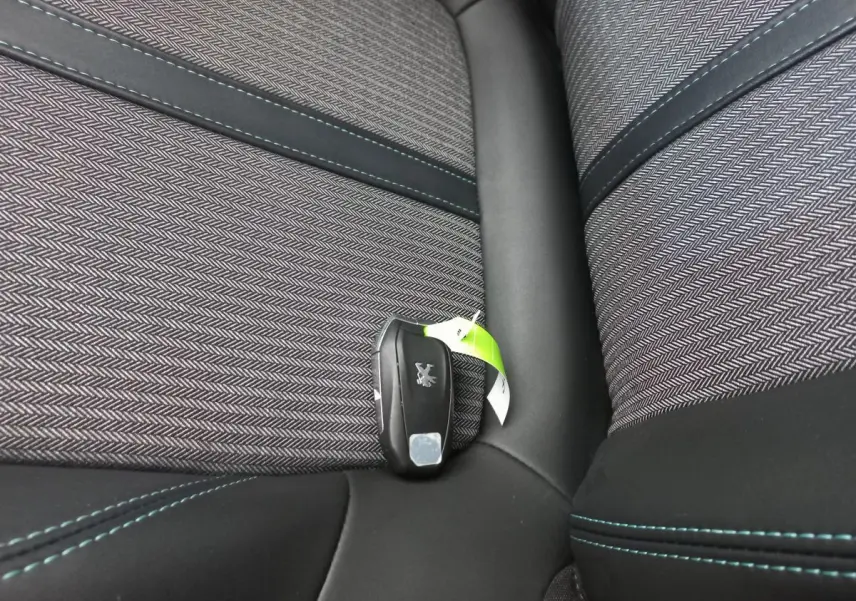 Clé Peugeot posée sur un siège tissu gris foncé avec surpiqûres bleues dans l'habitacle du 5008 Allure Pack.