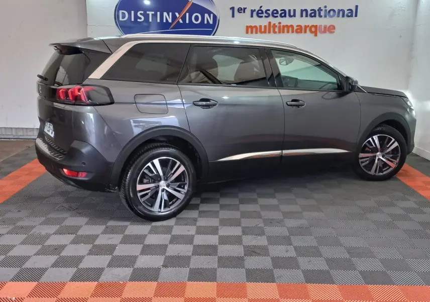 Peugeot 5008 gris foncé vue de profil côté droit, avec jantes alliage et toit noir en arrière-plan intérieur showroom.