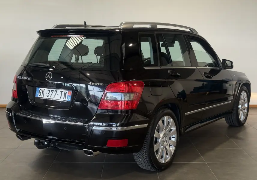 Vue 3/4 arrière droite d'un Mercedes GLK 220 CDI noir 4Matic de 2010 avec jantes alliage et attelage visible