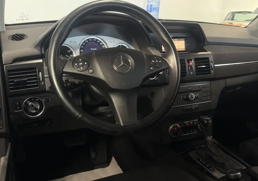 Intérieur noir du Mercedes GLK 220 cdi 170 ch 4Matic 2010, vue centrée sur le volant et tableau de bord avec boîte auto.